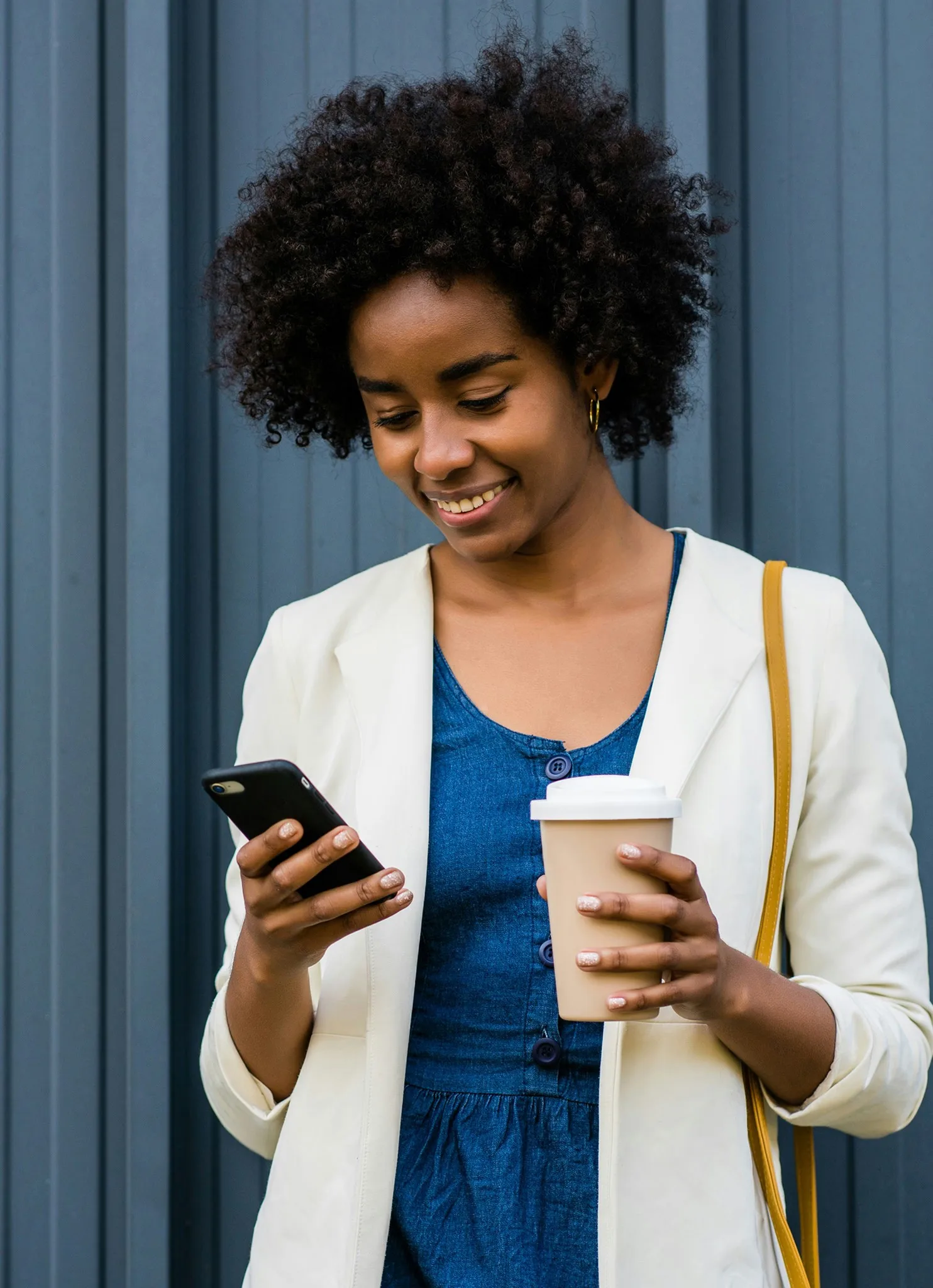 Businesswoman checking her phone while holding a coffee cup
